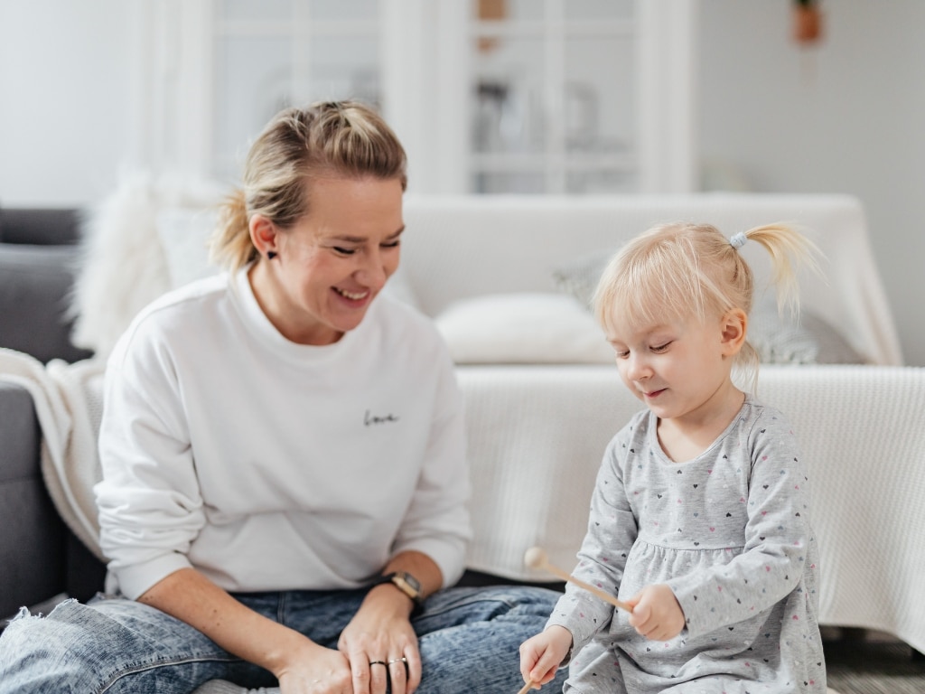 Mother sits on the living room floor playing with her daughter, highlighting Scullion LAW's expertise in Child Law services.